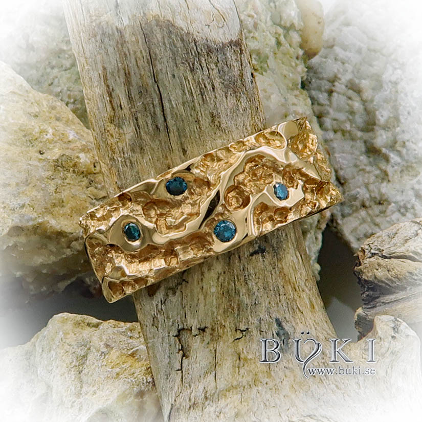 Ravinsjöar-bred guldring i 18k med blå diamanter